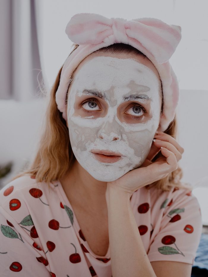 our-services-01 A woman relaxes in a skincare routine, wearing a facial mask and headband indoors.